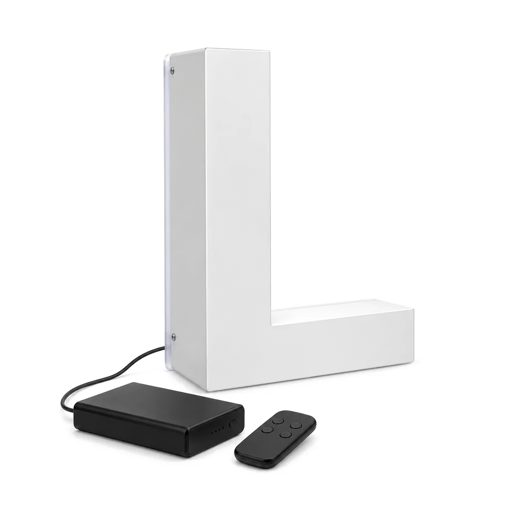 White halo-lit letter L with a black rechargeable battery box and a small remote beside it, on white